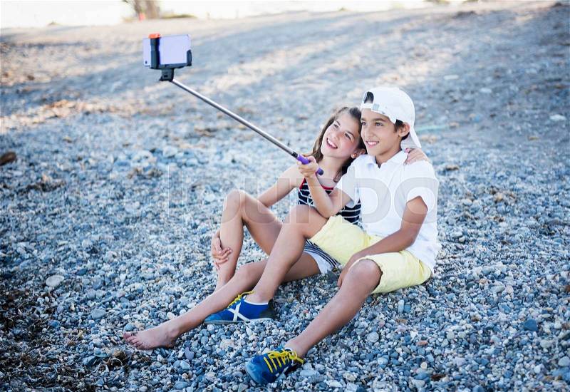 Boy and girl on the beach doing selfie, stock photo