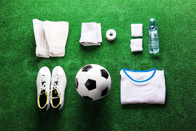 Soccer ball,cleats and various football stuff against artificial turf. Studio shot on green background. Flat lay, knolling, stock photo