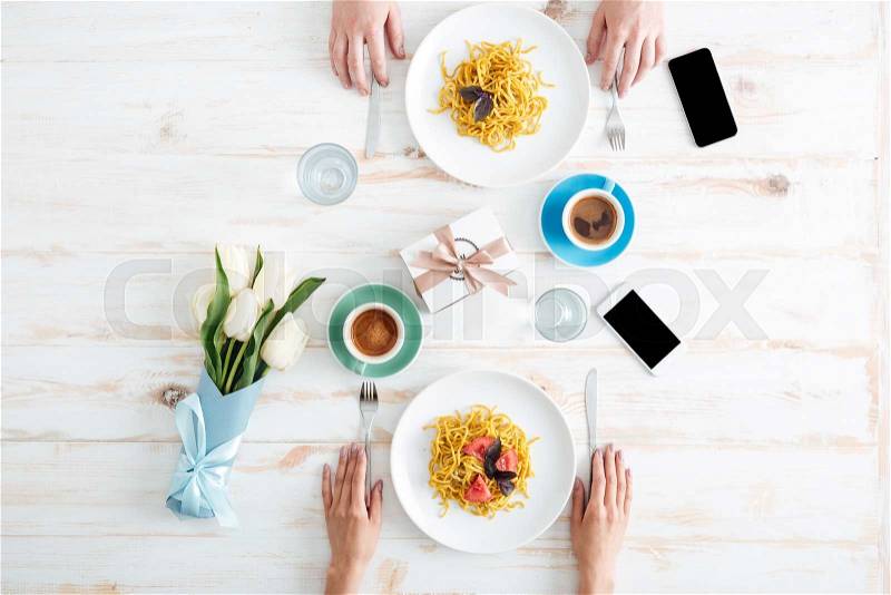 Hands of couple eating pasta and drinking coffee on table, stock photo
