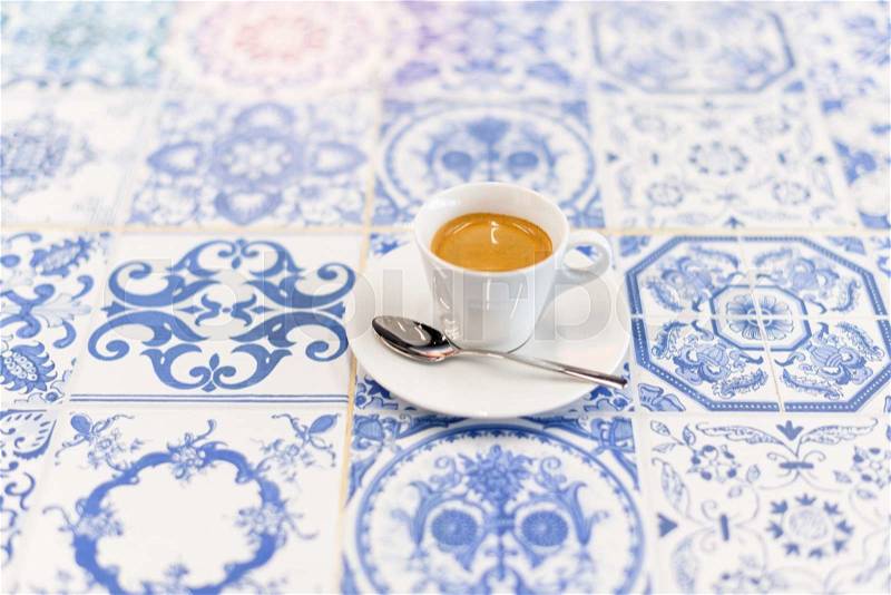 Espresso coffee in tiny cup on Moroccan or vintage azulejos tiles, stock photo