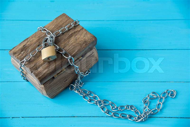 Padlock locked wooden treasure box on blue wood background, stock photo