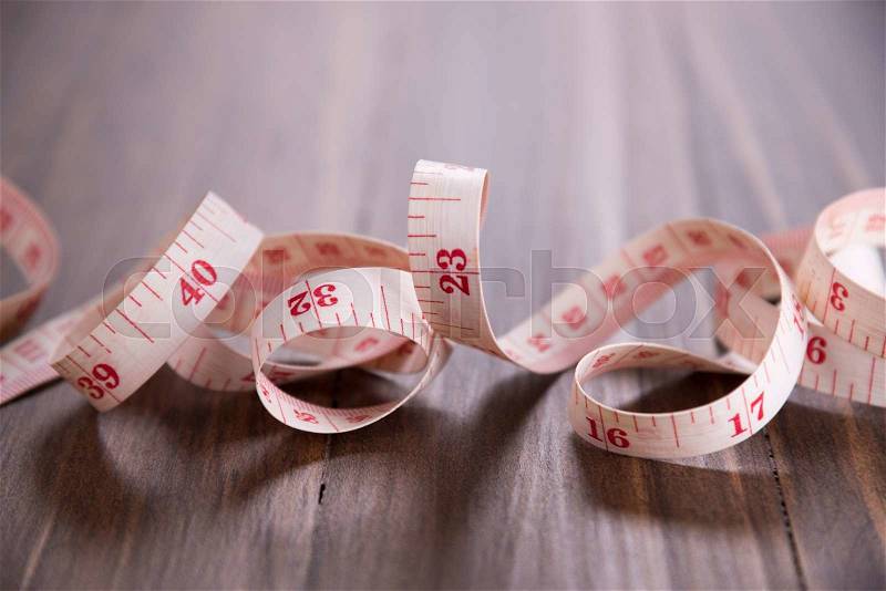 White measuring tape on wood background, stock photo