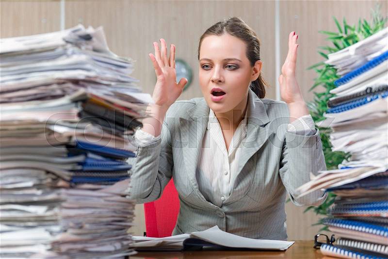 Woman under stress from excessive paper work, stock photo