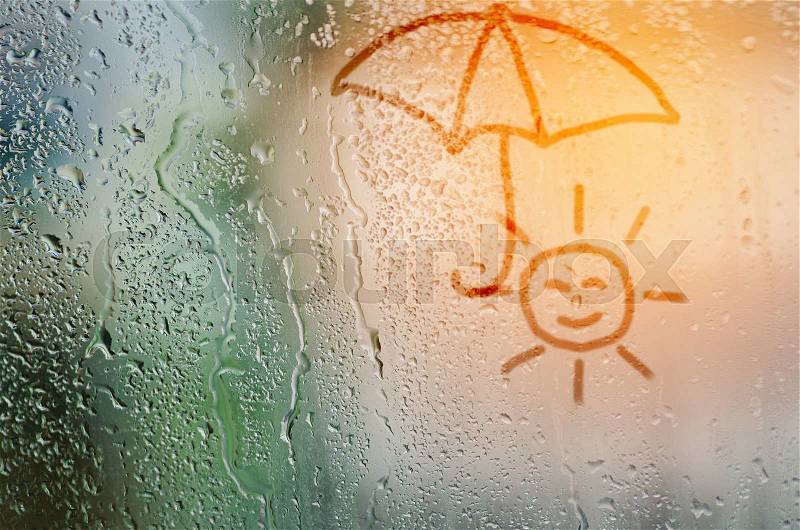 Draw sun holding umbella on natural water drops glass window background, stock photo
