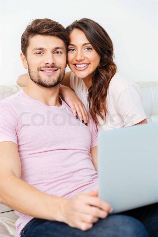 Happy young couple sitting on couch using laptop isolated on white background, stock photo