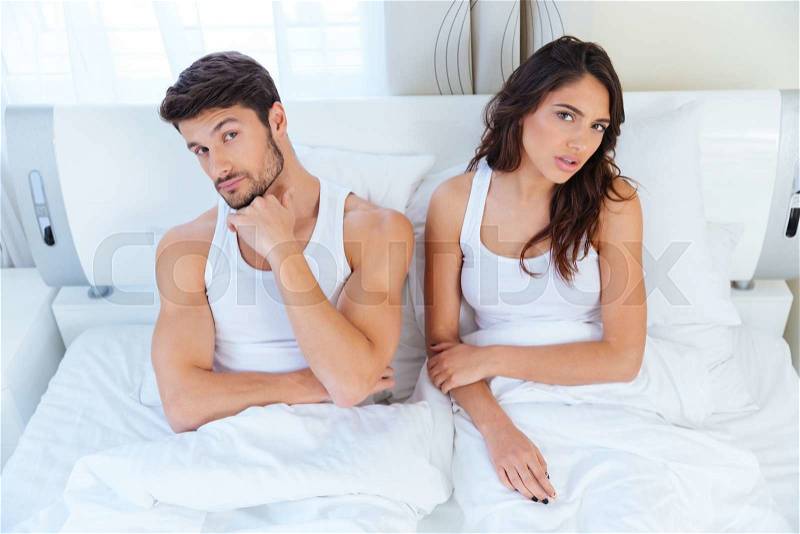 Unhappy couple not talking after an argument in bed at home, stock photo