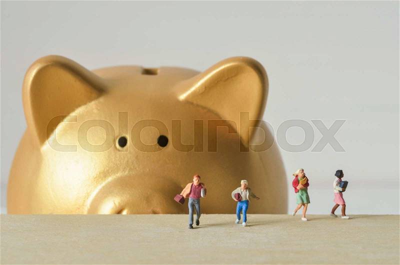 Miniature people run away from gold piggy bank, stock photo