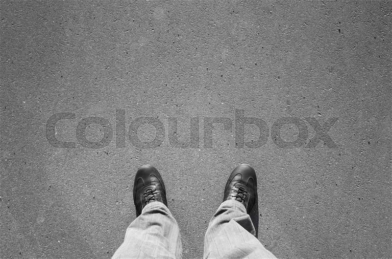 Male feet in black new shining leather shoes standing on urban asphalt pavement, stock photo
