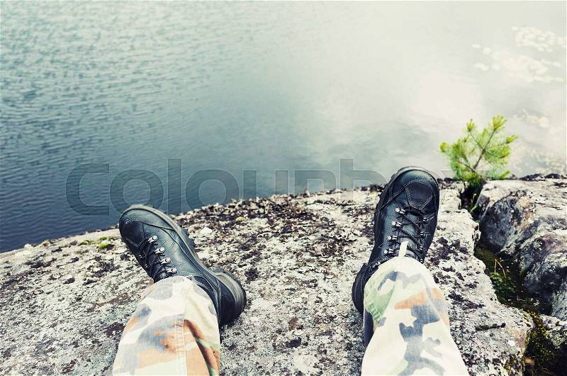 Male feet in camouflage pants and black rough shoes, travel lifestyle background. Cold tonal correction photo filter, old style effect, stock photo