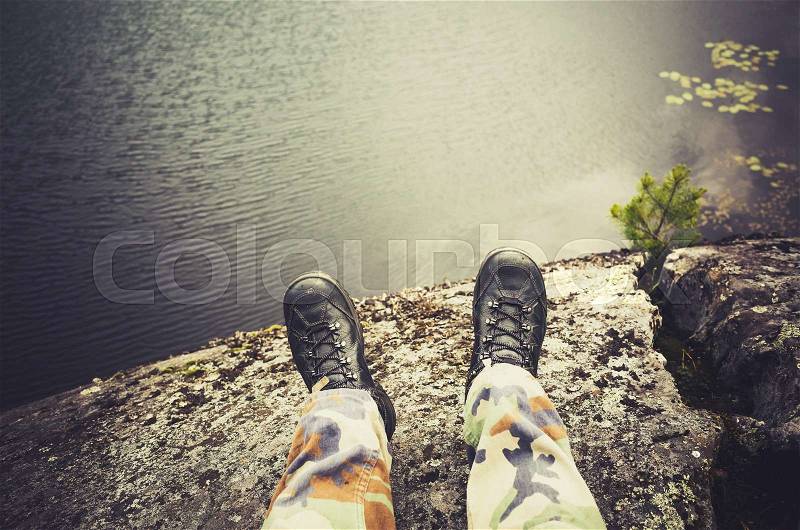 Male feet in camouflage pants and black rough shoes, travel lifestyle background. Vintage tonal correction photo filter, old style effect, stock photo