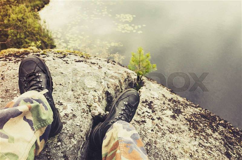 Soldier feet in camouflage pants and black rough shoes, modern army background. Vintage tonal correction photo filter, old style effect, stock photo