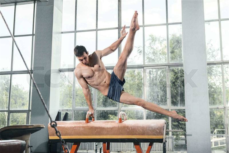 The sportsman the guy performing difficult exercise, sports gymnastics, stock photo