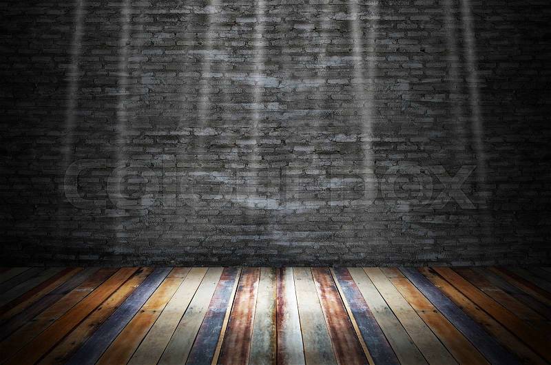 Light in dark room with colorful wooden floor and grunge stone wall, stock photo