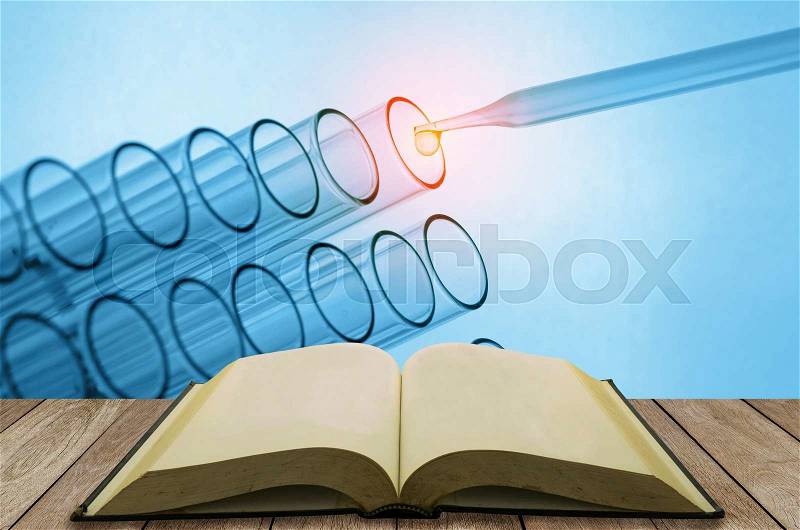Open book on wooden table with science laboratory test tubes background, stock photo