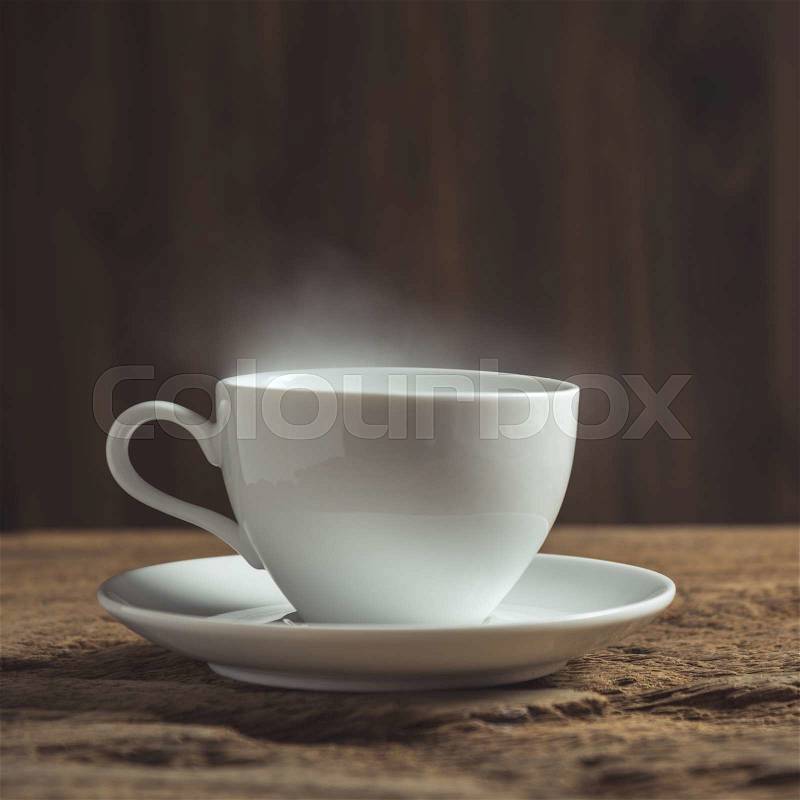White coffee cup with smoke on wood table, stock photo