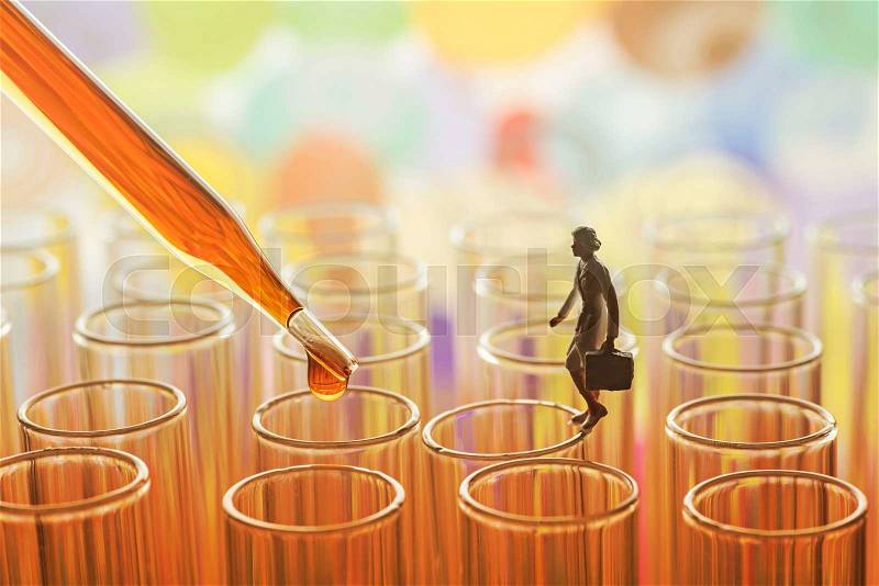 Miniature scientist checking chemical in laboratory test tube, stock photo