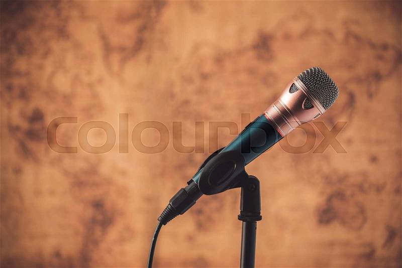 Black microphone with blurred old world map background, stock photo
