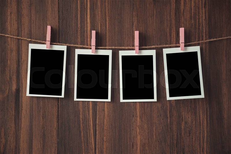 Empty photo frames hanging with clothespins on wooden background, stock photo