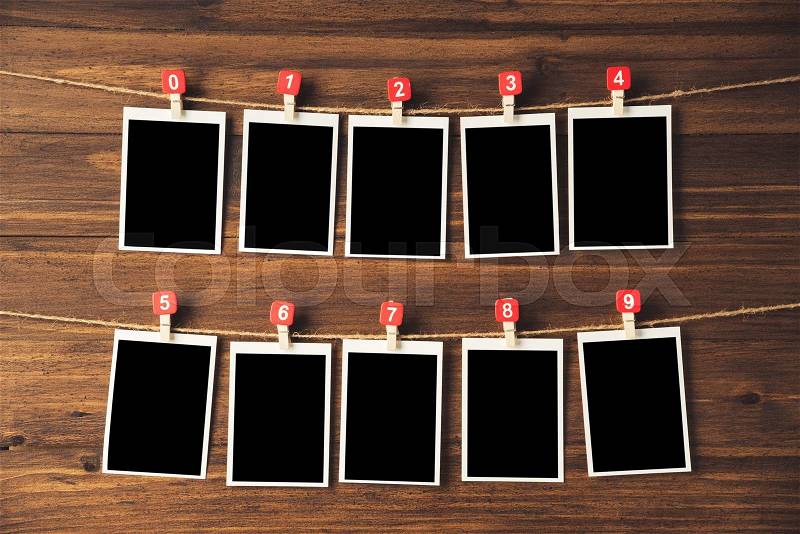 Empty photo frames hanging with clothespins on wooden background, stock photo