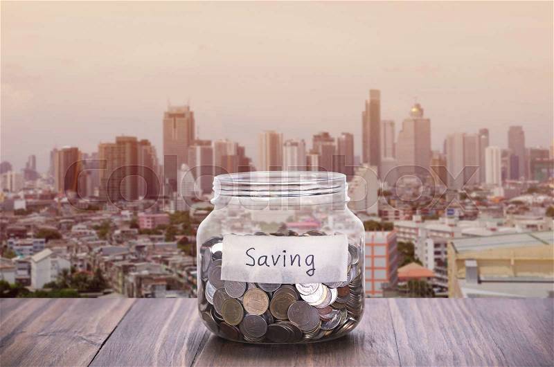 Saving Glass jar with coin with city background, stock photo