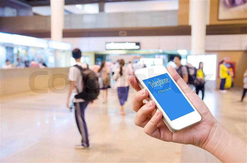 Hand holding mobile phone for mobile check in with blurred event background, stock photo