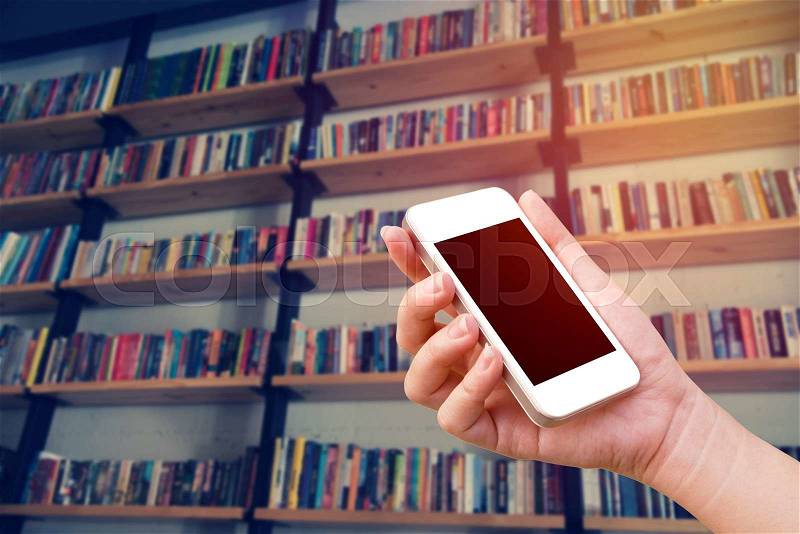 Woman hand using the phone tablet with book shelf background, stock photo