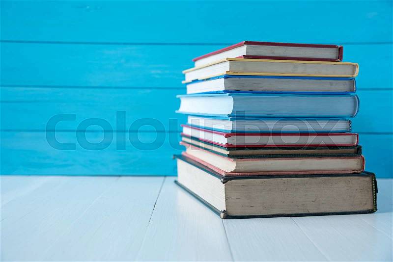 Book stack with blue wooden wall background, stock photo