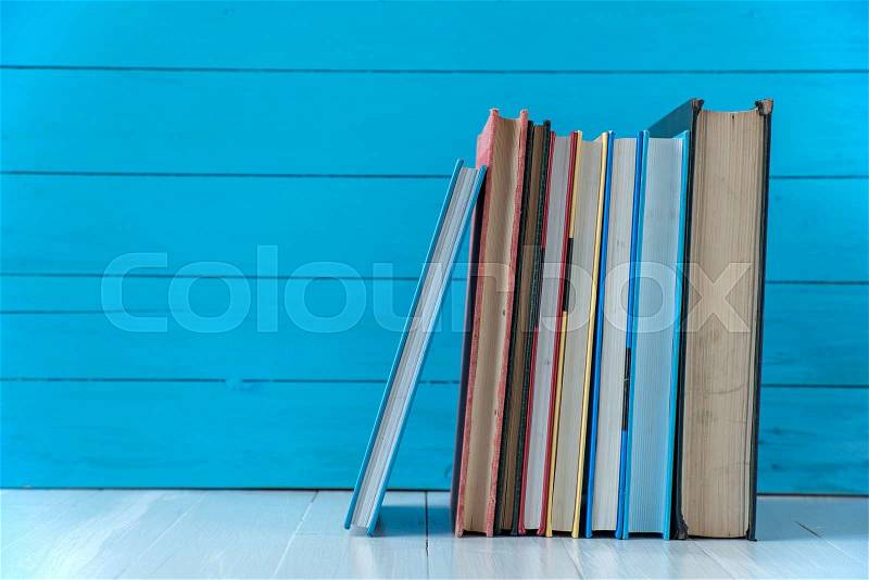 Book stack with blue wooden wall background, stock photo