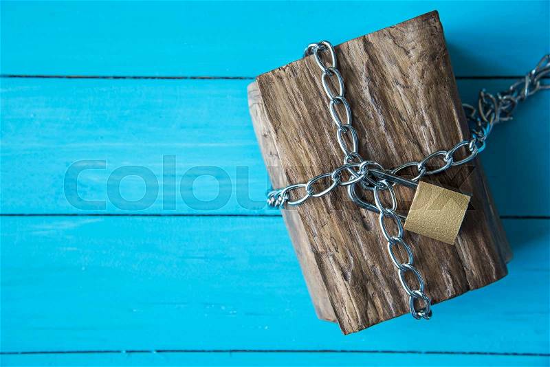 Locked wooden treasure box on blue wood background, stock photo