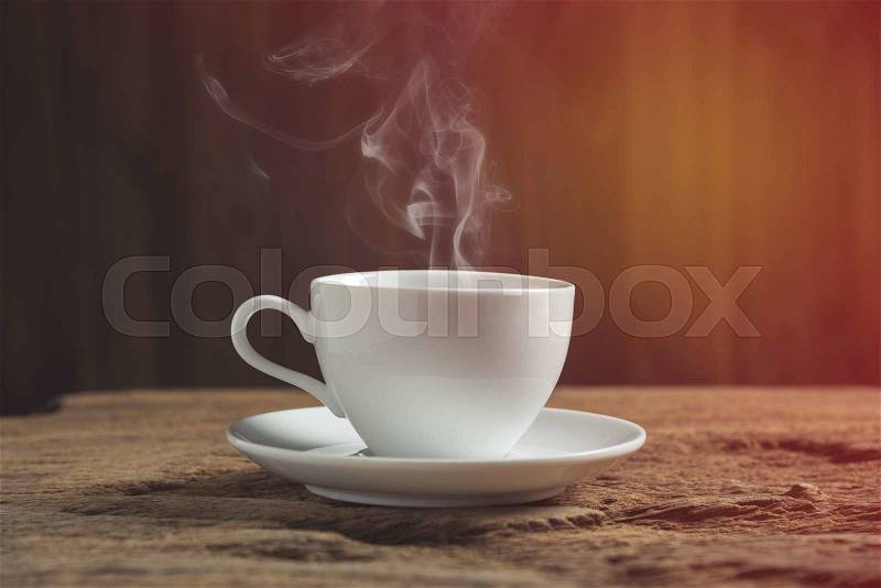 White coffee cup with smoke on wooden table, stock photo