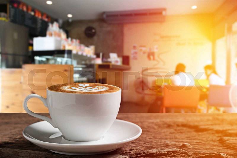 White coffee cup on wooden table with coffee bar background, stock photo
