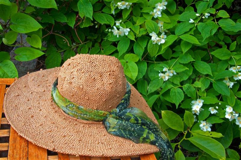 A straw hat on a table in a garden, stock photo