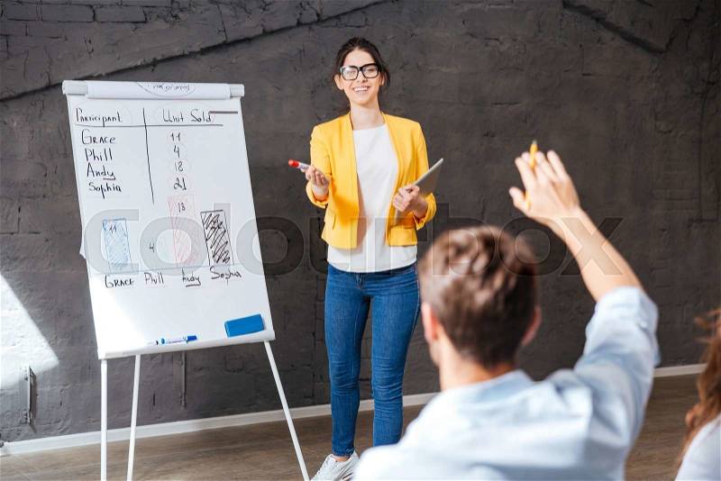 Cheerful young business woman making presentation and answering questions of audience, stock photo