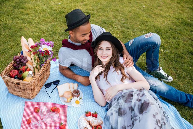 Relaxed young couple lying and having picnic on lawn, stock photo