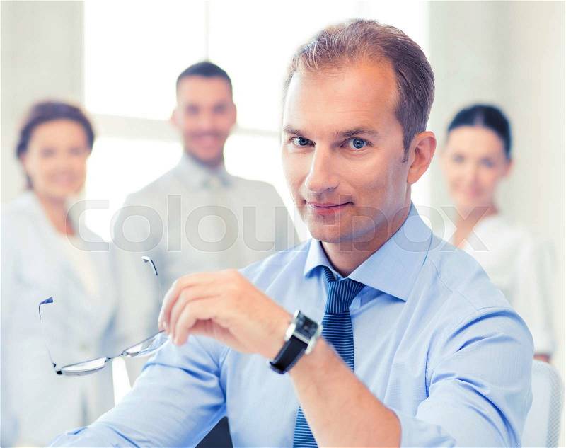 Businessman with glasses writing in notebook in office, stock photo