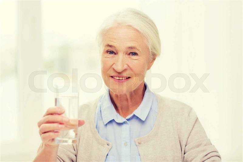 Age, health care and people concept - happy senior woman with glass of water at home, stock photo