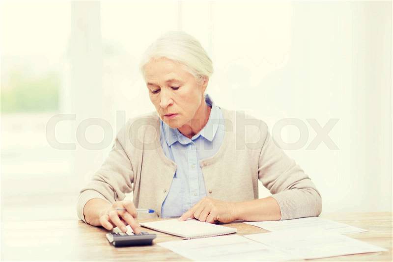Business, savings, annuity insurance, age and people concept - senior woman with papers or bills and calculator writing at home, stock photo