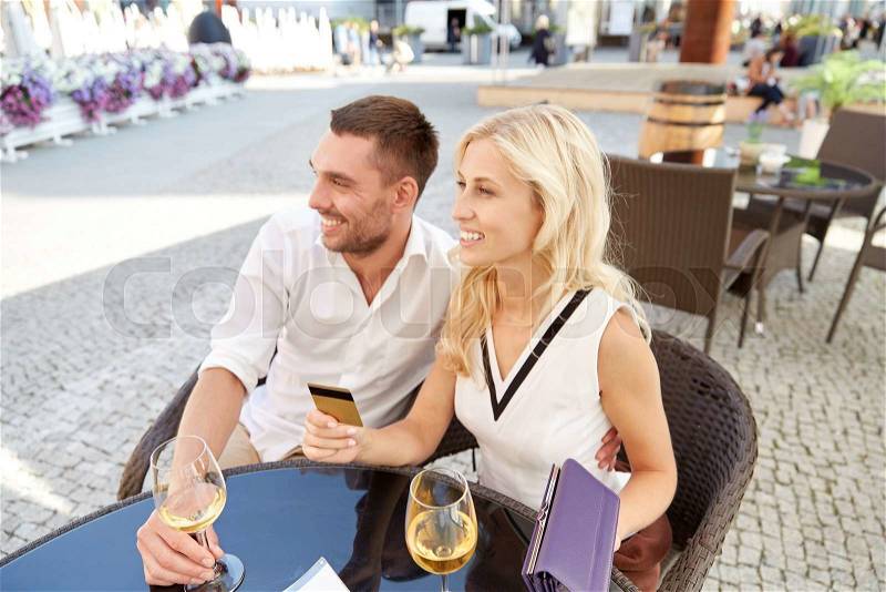 Date, people, payment and finances concept - happy couple with wallet, credit card and wine glasses paying bill at restaurant, stock photo