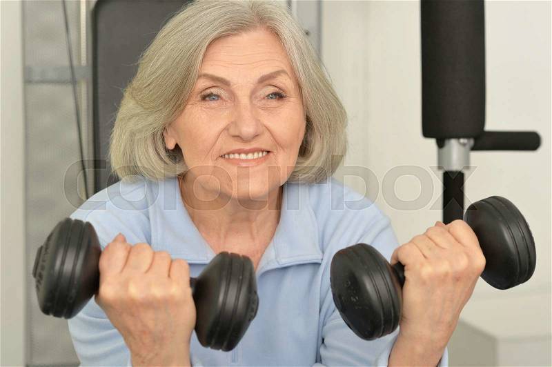 Portrait of elderly woman exercising in gym, stock photo