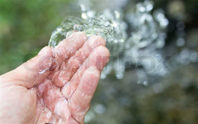Hand in tap water in nature, stock photo