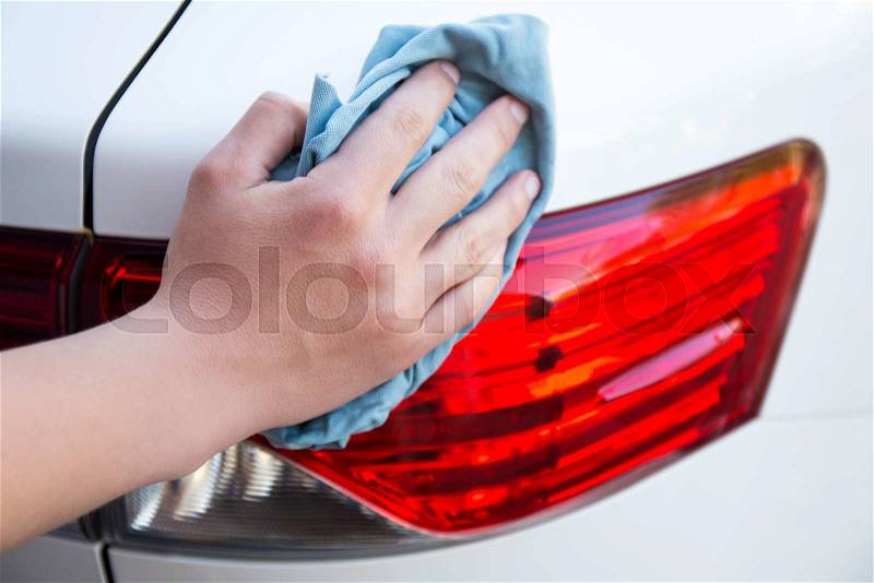 Male hand washing rear car lights with microfiber cloth, stock photo