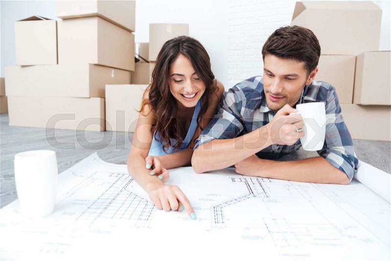 Happy couple looking at new house blueprints at home, stock photo