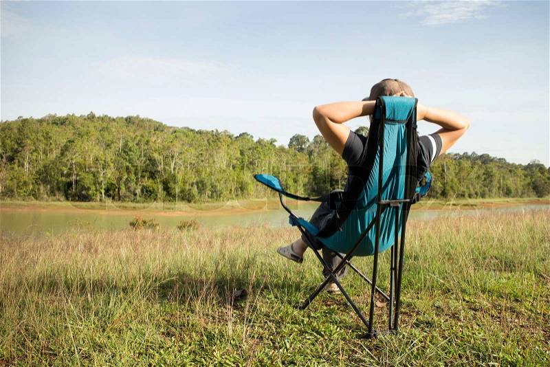 Thai woman sitting on the chair in the field at Khao Yai National park, Thailand, stock photo