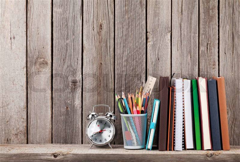 Wooden shelf with books and supplies in front of wooden wall. View with copy space, stock photo