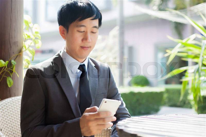 Young Asian businessman using phone in the outdoor scene, stock photo