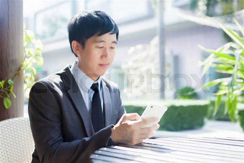 Young Asian businessman using phone in the outdoor scene, stock photo