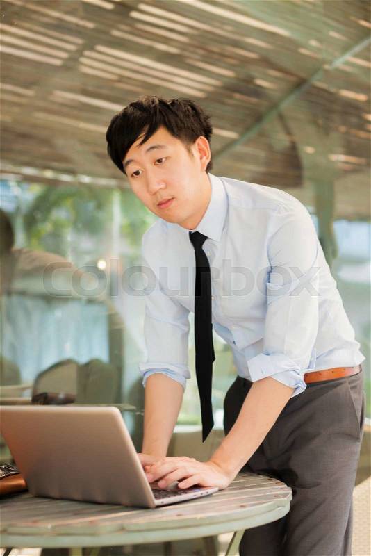 Young Asian businessman working on computer while standing in outdoor , stock photo