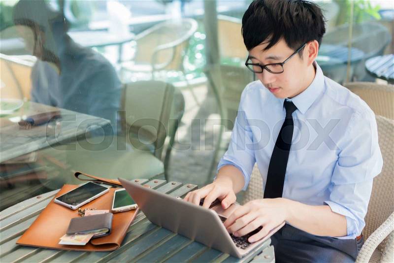 Young Asian businessman working with his laptop in outdoor scene, stock photo