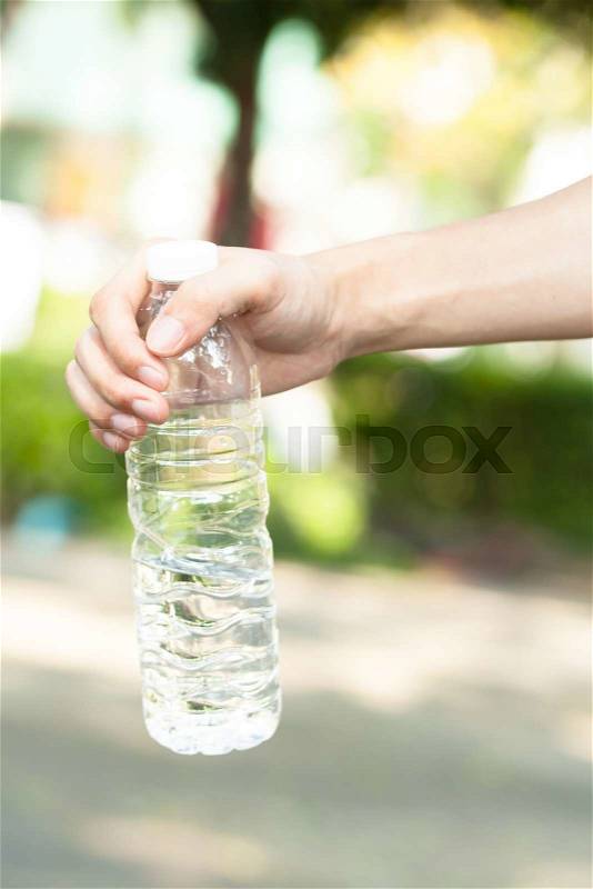 Young people hand holding a bottle of water - hydration concept, stock photo