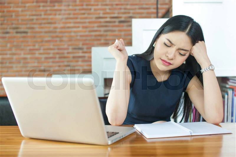 Asian Woman Thinking and Serious in front of Laptop in Modern Office, stock photo